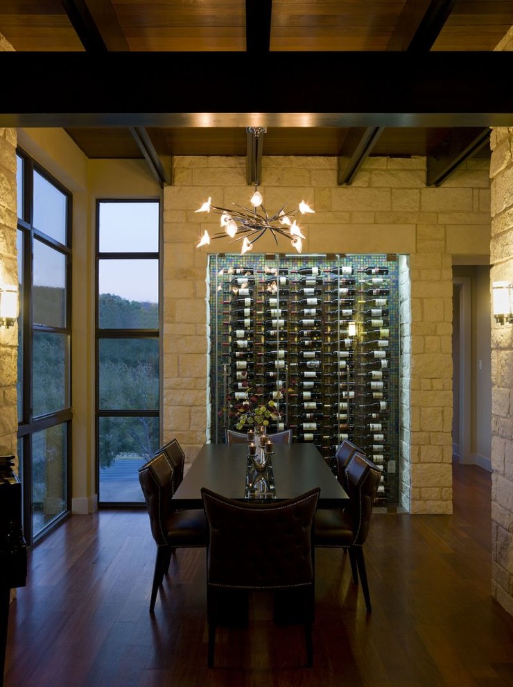Large contemporary wine cellar in Austin with dark hardwood floors and display racks.