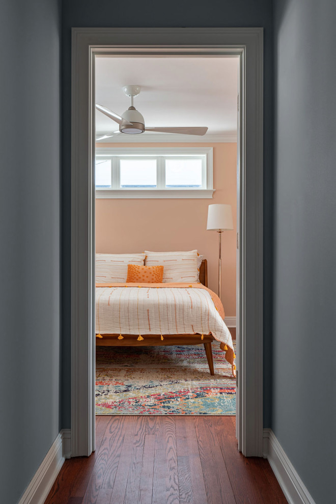 Идея дизайна: большая гостевая спальня (комната для гостей) в стиле неоклассика (современная классика) с оранжевыми стенами, паркетным полом среднего тона и коричневым полом