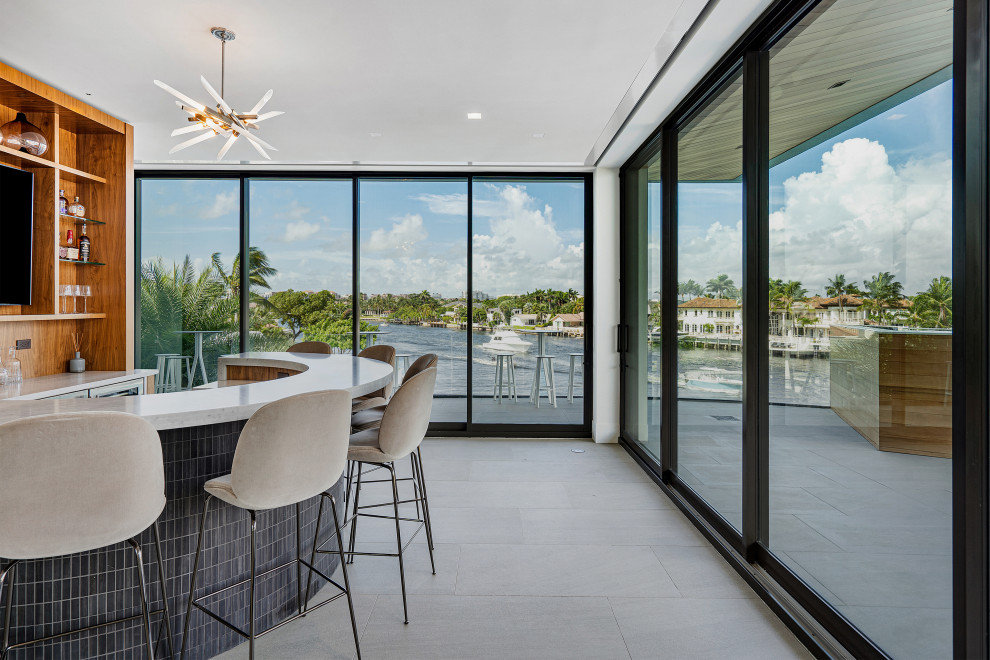 Example of a large trendy u-shaped porcelain tile and gray floor seated home bar design in Miami with a drop-in sink, flat-panel cabinets, medium tone wood cabinets, marble countertops, wood backsplash and white countertops