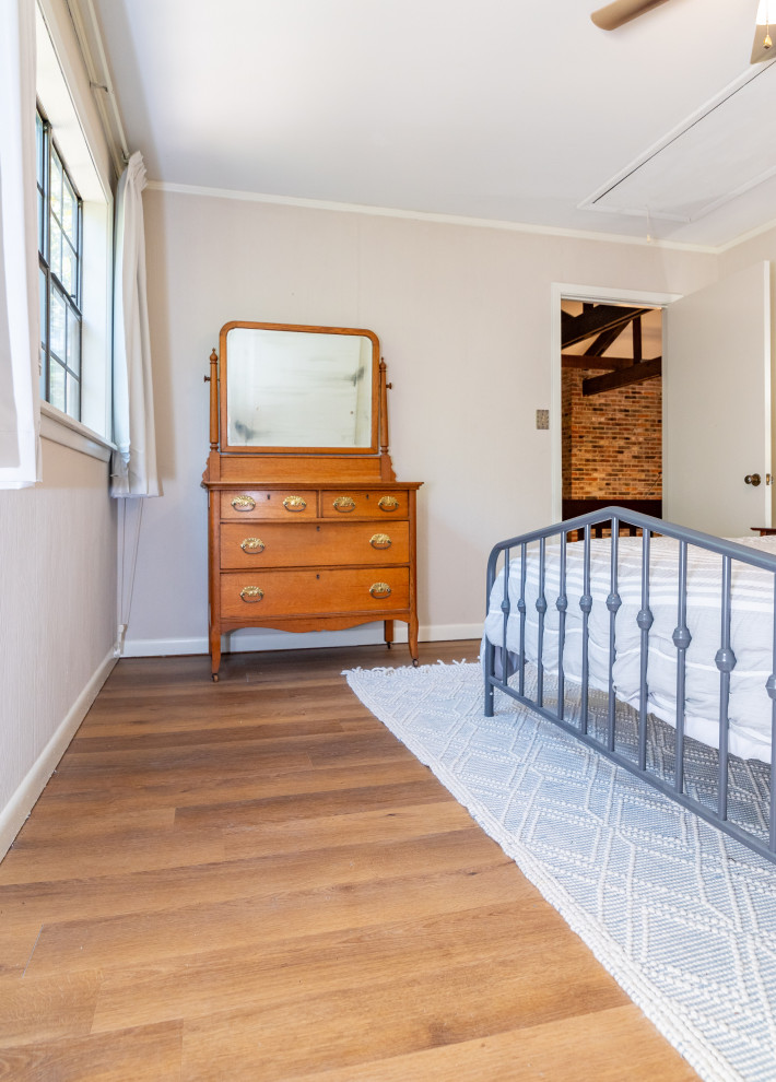 Imagen de dormitorio principal de estilo de casa de campo grande con paredes beige, suelo vinílico y suelo marrón