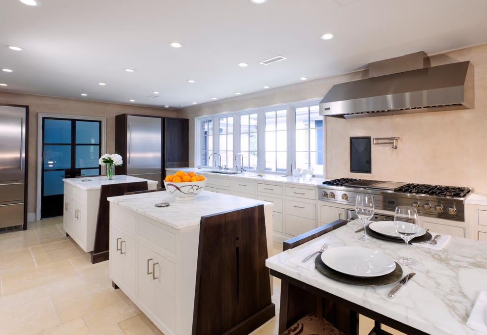 Example of a transitional l-shaped kitchen design in Charlotte with beaded inset cabinets, white cabinets, stainless steel appliances and two islands