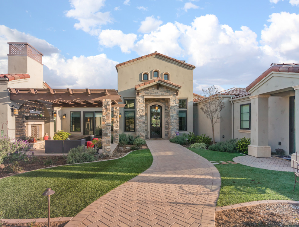 Mediterranean one-storey stucco beige house exterior in San Diego with a gable roof and a tile roof.