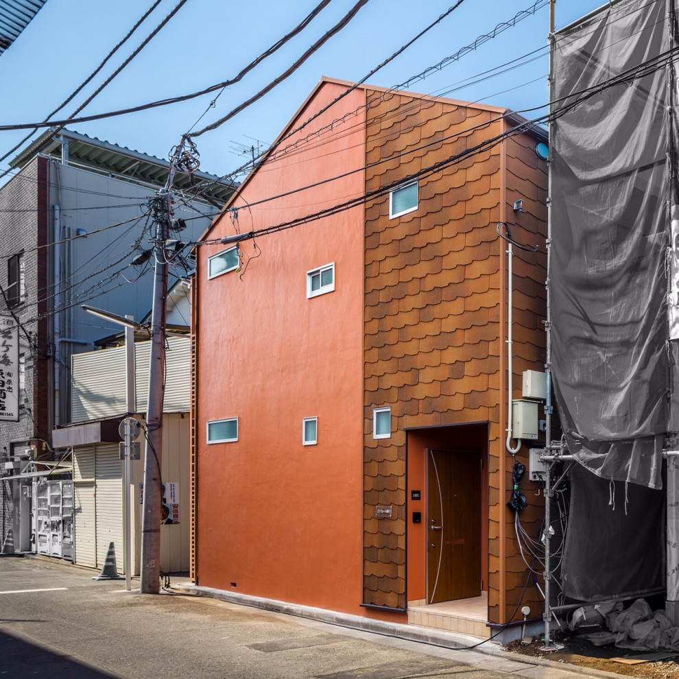 This is an example of a mid-sized scandinavian two-storey orange house exterior in Tokyo with concrete fiberboard siding, a gable roof and a shingle roof.