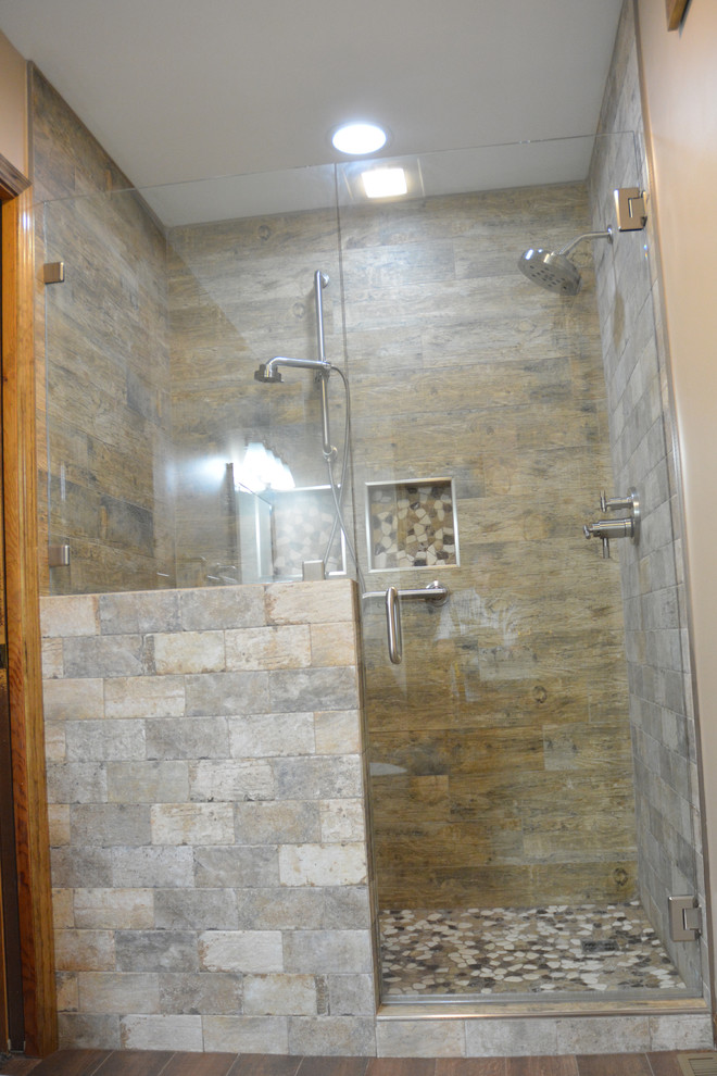 Example of a mid-sized mountain style master brown tile and ceramic tile ceramic tile and brown floor alcove shower design with raised-panel cabinets, light wood cabinets, a two-piece toilet, beige walls, an integrated sink, marble countertops, a hinged shower door and gray countertops