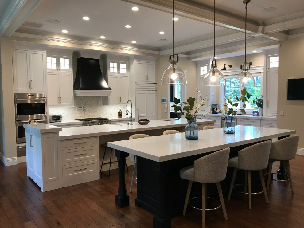 This is an example of an expansive traditional l-shaped eat-in kitchen in San Francisco with a double-bowl sink, beaded inset cabinets, white cabinets, quartz benchtops, white splashback, marble splashback, white appliances, medium hardwood floors, multiple islands, brown floor, white benchtop and coffered.