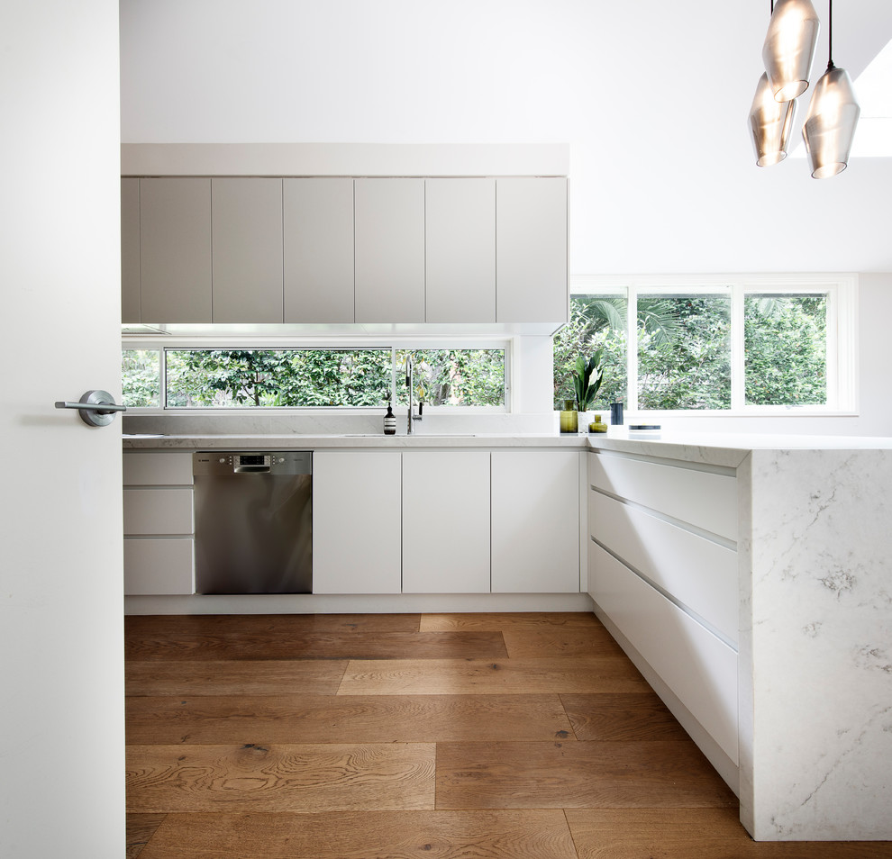 Design ideas for a large midcentury galley kitchen pantry in Sydney with an undermount sink, flat-panel cabinets, grey cabinets, quartz benchtops, window splashback, stainless steel appliances, light hardwood floors, a peninsula, beige floor and multi-coloured benchtop.