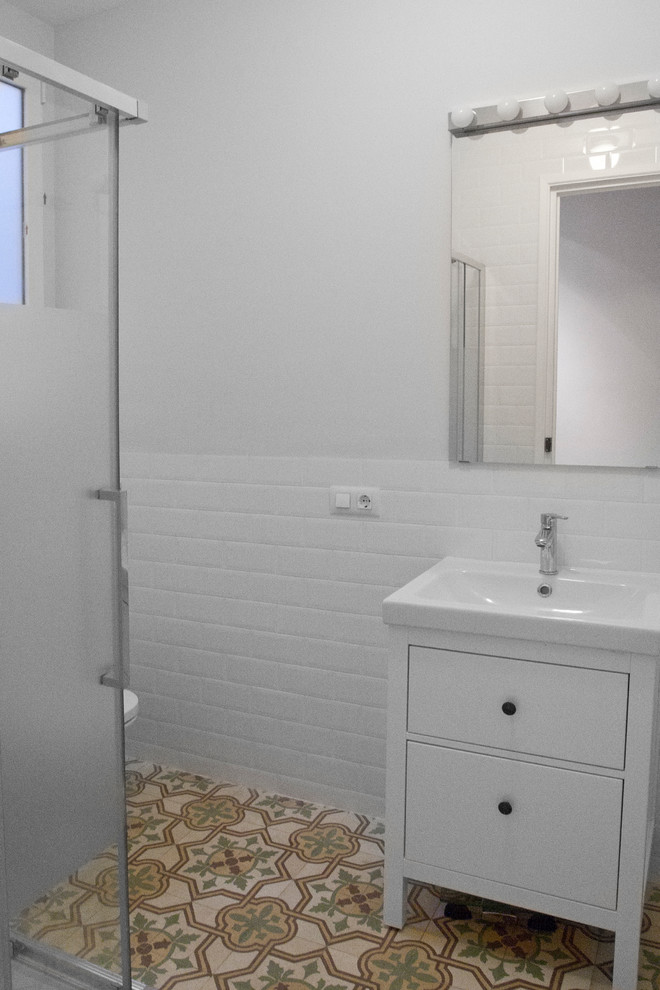 Photo of a small transitional powder room in Valencia with furniture-like cabinets, white cabinets, white walls, ceramic floors, an integrated sink and a two-piece toilet.