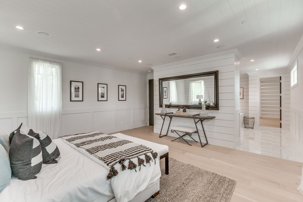 Large contemporary master bedroom in Los Angeles with white walls, light hardwood floors, no fireplace and brown floor.