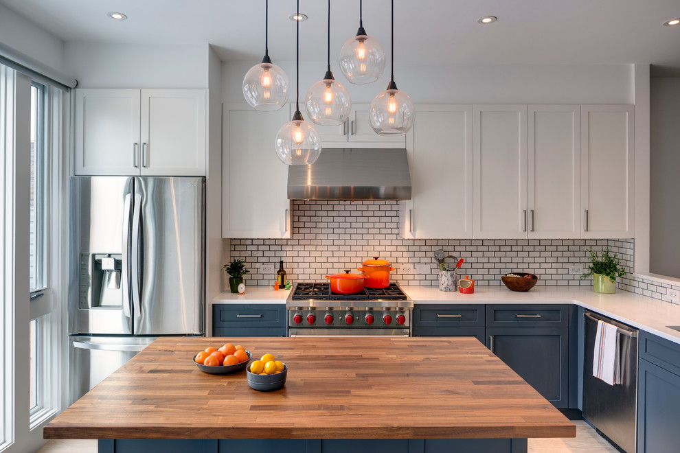 Design ideas for a transitional l-shaped kitchen in New York with shaker cabinets, grey cabinets, quartz benchtops, white splashback, stainless steel appliances, light hardwood floors, with island and subway tile splashback.