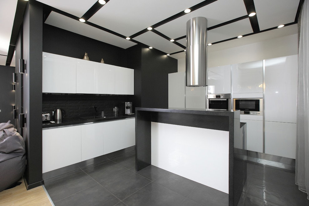 Contemporary l-shaped kitchen in Other with flat-panel cabinets, white cabinets, black splashback, brick splashback, with island, grey floor, grey benchtop and stainless steel appliances.