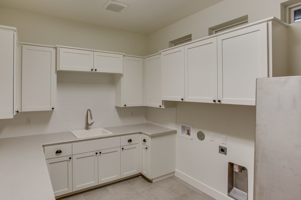 Inspiration for a mid-sized transitional u-shaped dedicated laundry room in Austin with a drop-in sink, white cabinets, white walls, a side-by-side washer and dryer, shaker cabinets, porcelain floors, solid surface benchtops, white floor and grey benchtop.