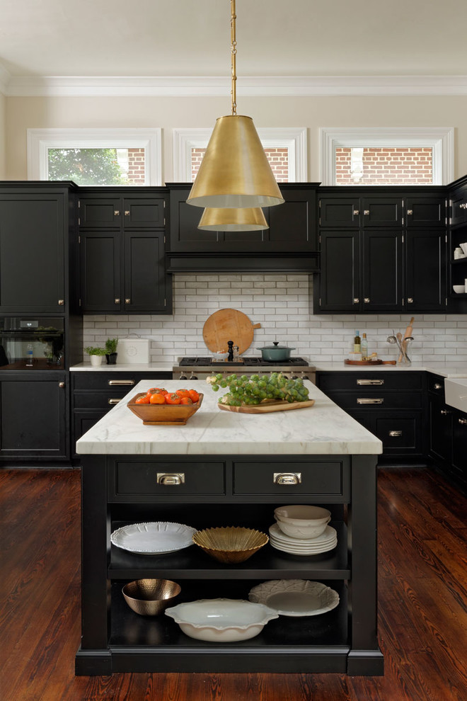 Design ideas for a large transitional l-shaped eat-in kitchen in DC Metro with a farmhouse sink, beaded inset cabinets, black cabinets, white splashback, subway tile splashback, stainless steel appliances, medium hardwood floors, with island, brown floor and quartzite benchtops.