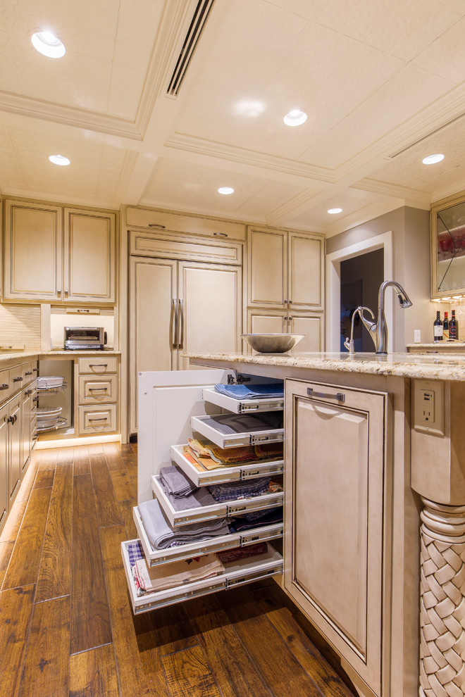 Enclosed kitchen - large transitional u-shaped medium tone wood floor enclosed kitchen idea in Austin with a double-bowl sink, raised-panel cabinets, white cabinets, granite countertops, beige backsplash, stone tile backsplash, paneled appliances and an island