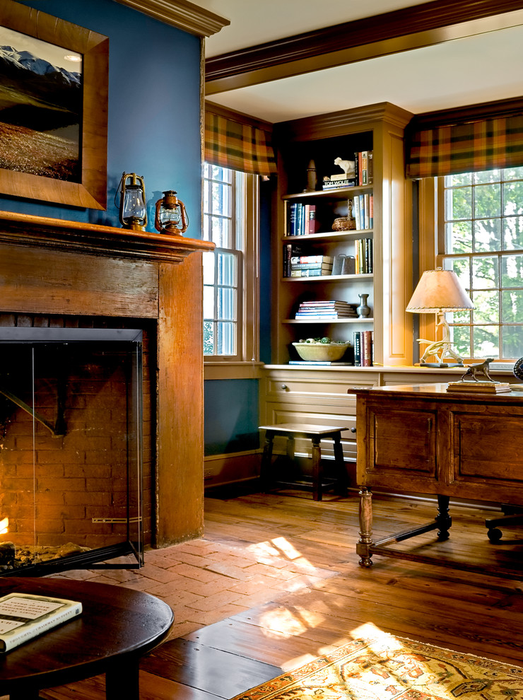 This is an example of a traditional home office in New York with blue walls, medium hardwood floors, a brick fireplace surround, a standard fireplace and brown floor.