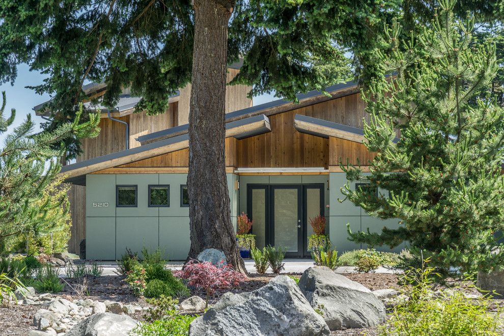 Ispirazione per la facciata di una casa contemporanea a due piani di medie dimensioni con rivestimento con lastre in cemento, copertura verde e tetto grigio