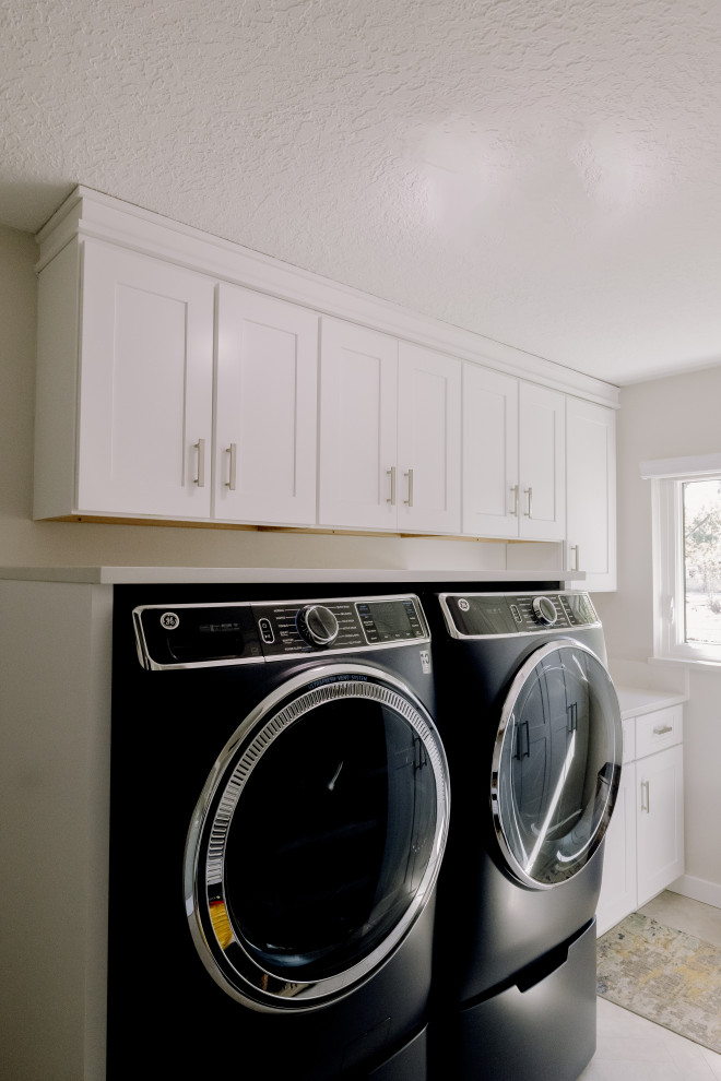 Idéer för mellanstora vintage parallella vitt tvättstugor enbart för tvätt, med luckor med profilerade fronter, vita skåp, bänkskiva i kvarts, vita väggar, klinkergolv i porslin, en tvättmaskin och torktumlare bredvid varandra och vitt golv