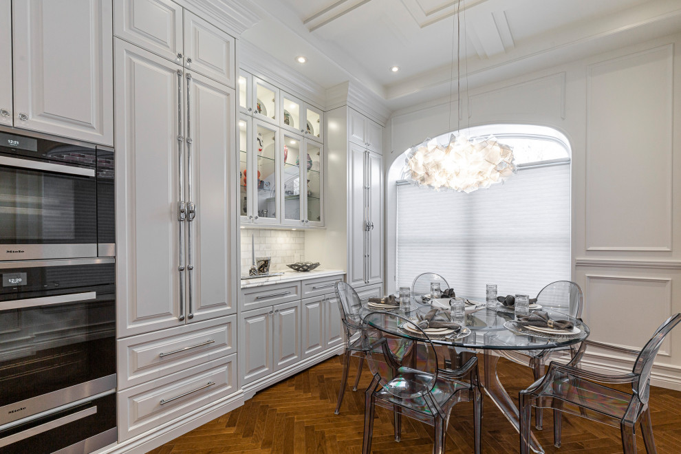 Large traditional l-shaped separate kitchen in Montreal with an undermount sink, raised-panel cabinets, white cabinets, marble benchtops, white splashback, marble splashback, stainless steel appliances, medium hardwood floors, with island, brown floor, white benchtop and coffered.