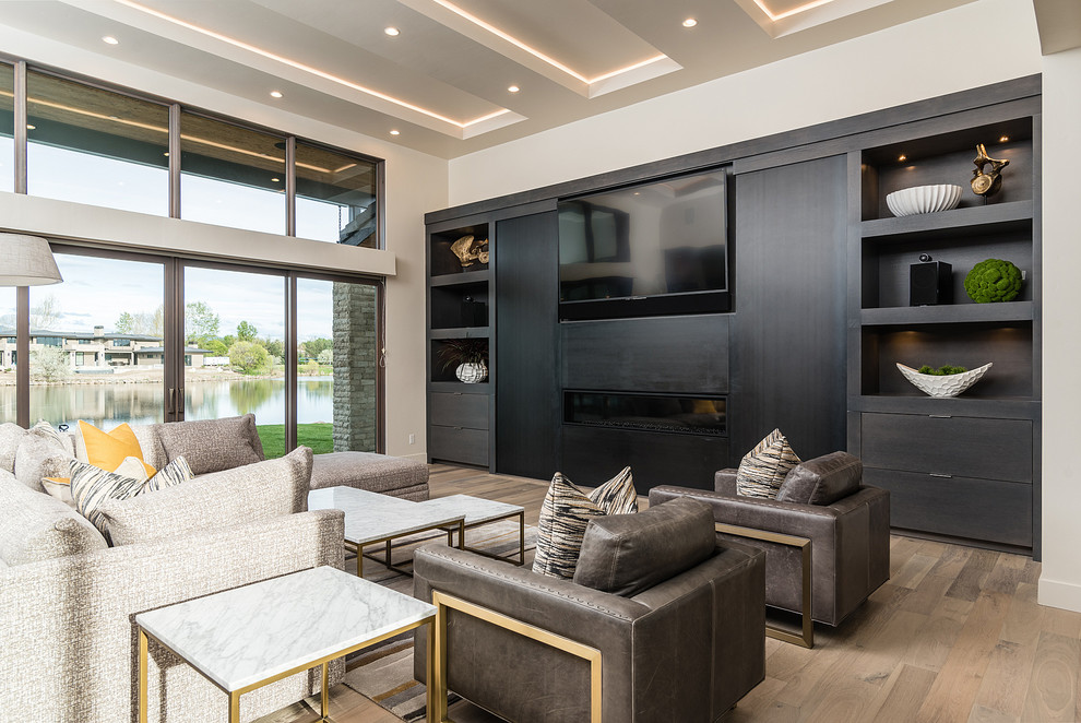Inspiration for a mid-sized modern open concept living room in Boise with medium hardwood floors, a built-in media wall, brown floor, beige walls and a ribbon fireplace.