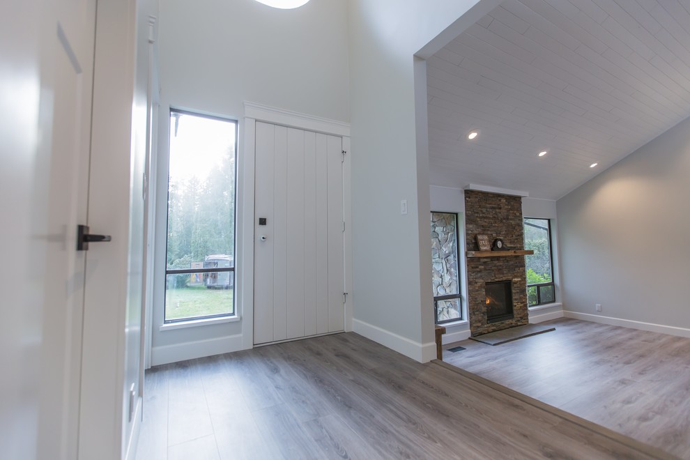 This is an example of an expansive modern front door in Vancouver with white walls, laminate floors, a single front door, a white front door and brown floor.