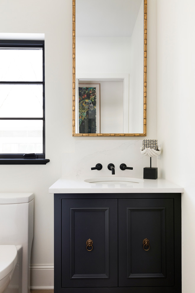 Photo of a small mediterranean powder room in Minneapolis with black cabinets, white walls, engineered quartz benchtops, white benchtops, recessed-panel cabinets, a one-piece toilet and an undermount sink.