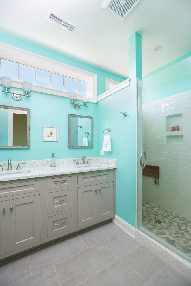 Photo of a small beach style master bathroom in Charleston with beaded inset cabinets, grey cabinets, a two-piece toilet, yellow tile, blue walls, ceramic floors, an undermount sink, marble benchtops, grey floor, a hinged shower door, white benchtops, a shower seat, a double vanity and a built-in vanity.