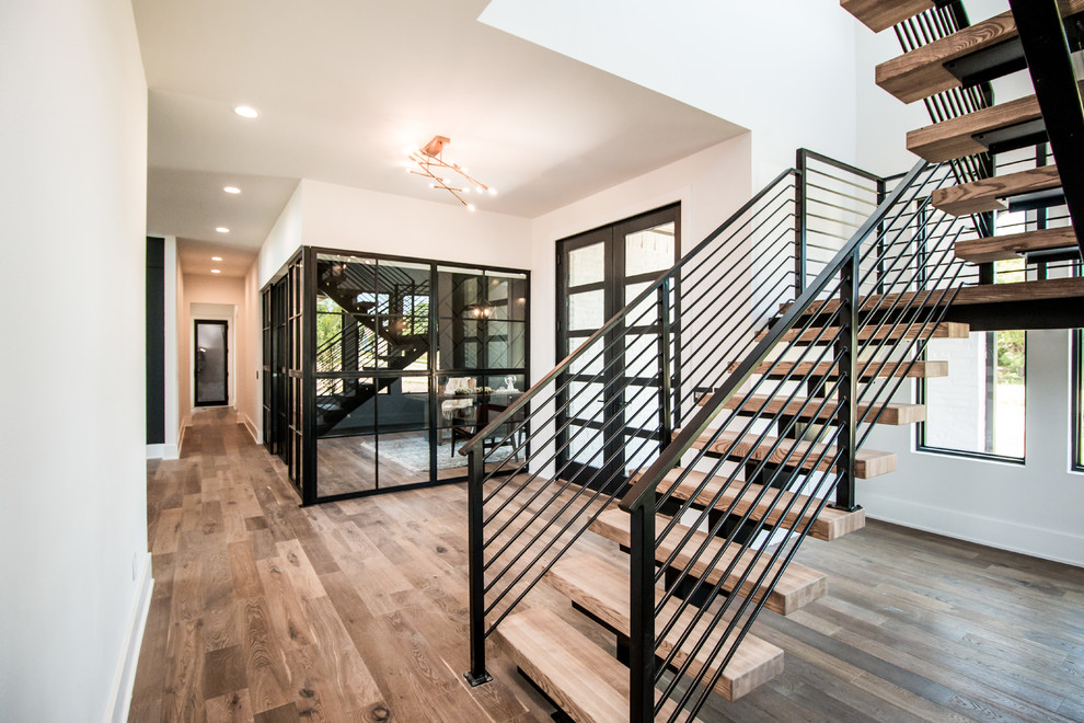 Large contemporary wood u-shaped staircase in Other with open risers and metal railing.