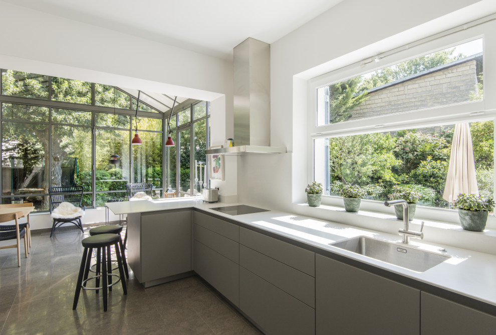 Photo of a mid-sized contemporary l-shaped kitchen in Paris with limestone floors, grey floor, an undermount sink, flat-panel cabinets, grey cabinets, stainless steel appliances, a peninsula and white benchtop.