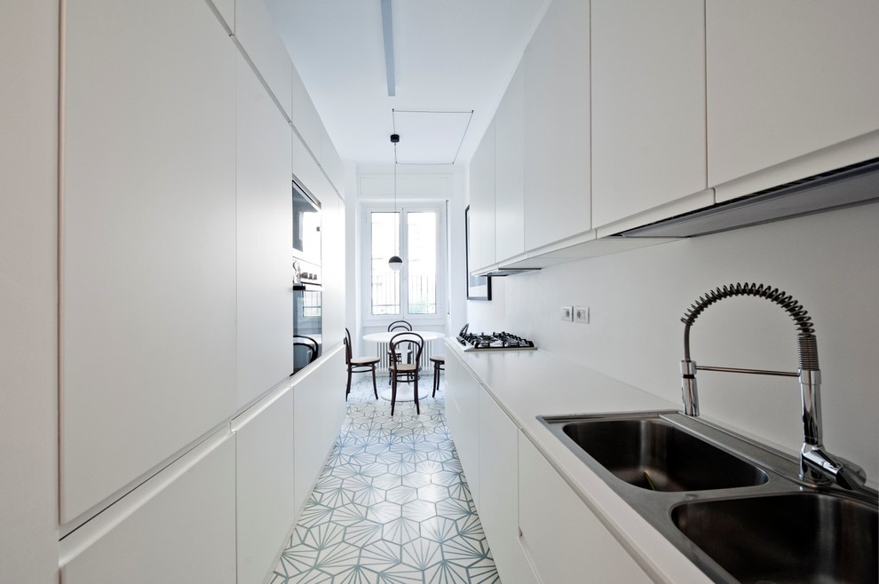 Inspiration for a mid-sized scandinavian galley eat-in kitchen in Milan with flat-panel cabinets, white cabinets, white splashback, cement tiles, no island, a drop-in sink, panelled appliances and blue floor.