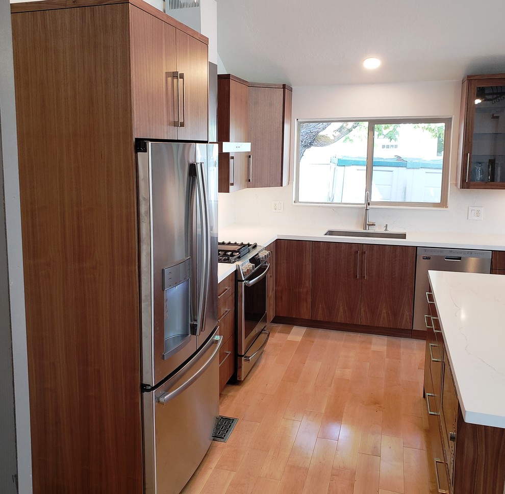 Inspiration for a large modern l-shaped eat-in kitchen in Salt Lake City with an undermount sink, flat-panel cabinets, medium wood cabinets, quartz benchtops, white splashback, stone slab splashback, stainless steel appliances, light hardwood floors, with island, brown floor and white benchtop.
