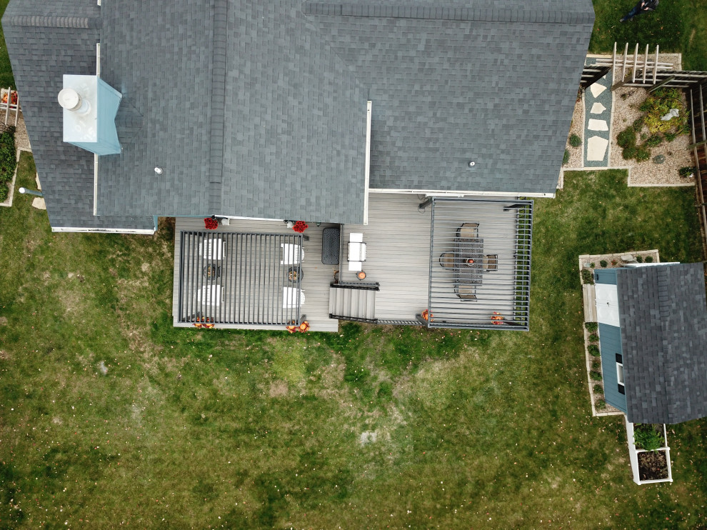 Large backyard ground level metal railing deck photo with a pergola