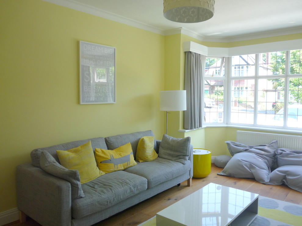 Mid-sized modern enclosed living room in London with yellow walls and medium hardwood floors.