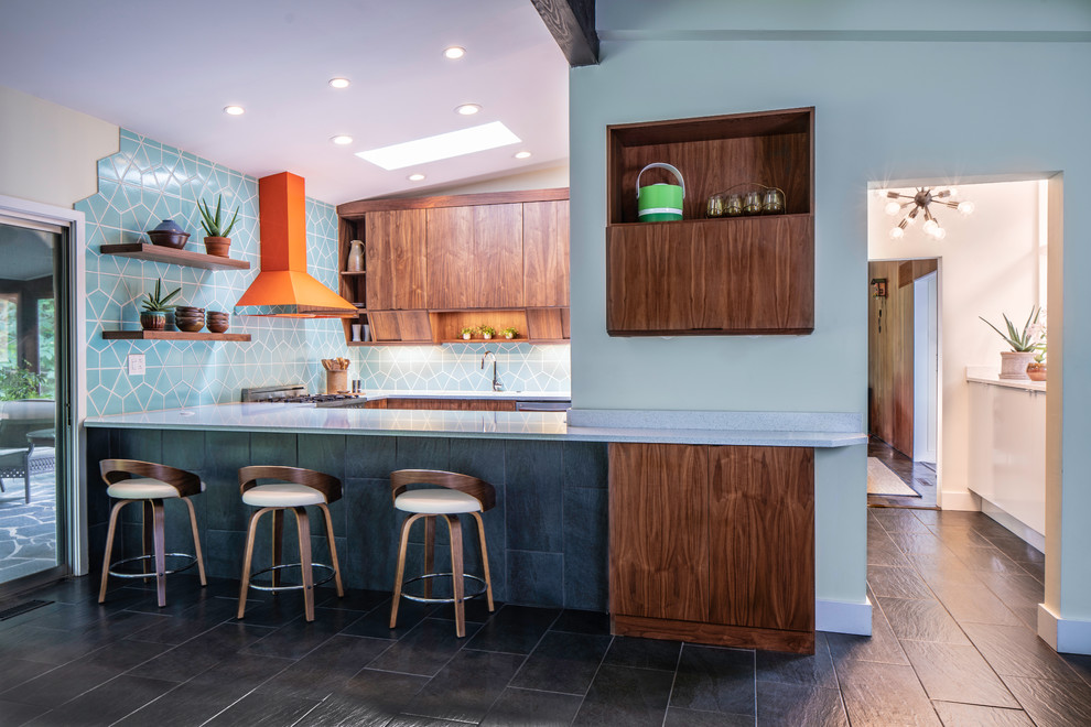 Inspiration for a mid-sized midcentury galley open plan kitchen in Cincinnati with a single-bowl sink, flat-panel cabinets, medium wood cabinets, quartz benchtops, ceramic splashback, coloured appliances, ceramic floors, with island, black floor and grey benchtop.
