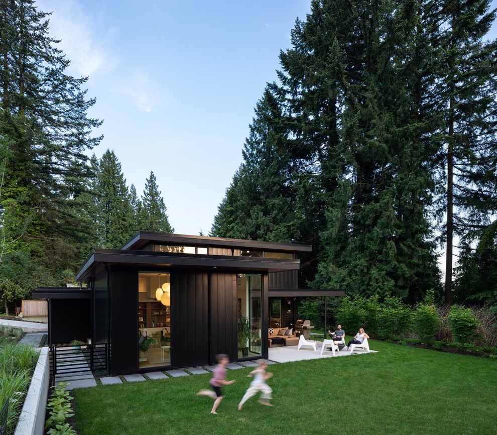 Design ideas for a scandinavian black house exterior in Vancouver with a shed roof and metal siding.