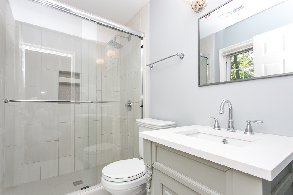 Photo of a mid-sized contemporary 3/4 bathroom in Wilmington with raised-panel cabinets, grey cabinets, an alcove shower, a two-piece toilet, blue walls, an integrated sink and solid surface benchtops.