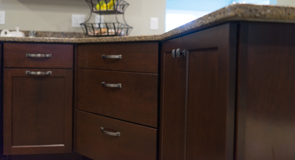 Mid-sized u-shaped ceramic tile enclosed kitchen photo with an undermount sink, shaker cabinets, dark wood cabinets, quartz countertops, brown backsplash, stainless steel appliances and a peninsula