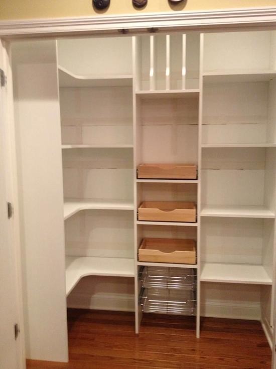 Photo of a mid-sized traditional gender-neutral walk-in wardrobe in Indianapolis with white cabinets and medium hardwood floors.
