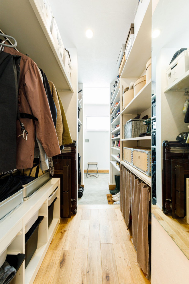 Foto de armario unisex urbano de tamaño medio con armarios abiertos, puertas de armario blancas, suelo de madera en tonos medios, suelo marrón y papel pintado