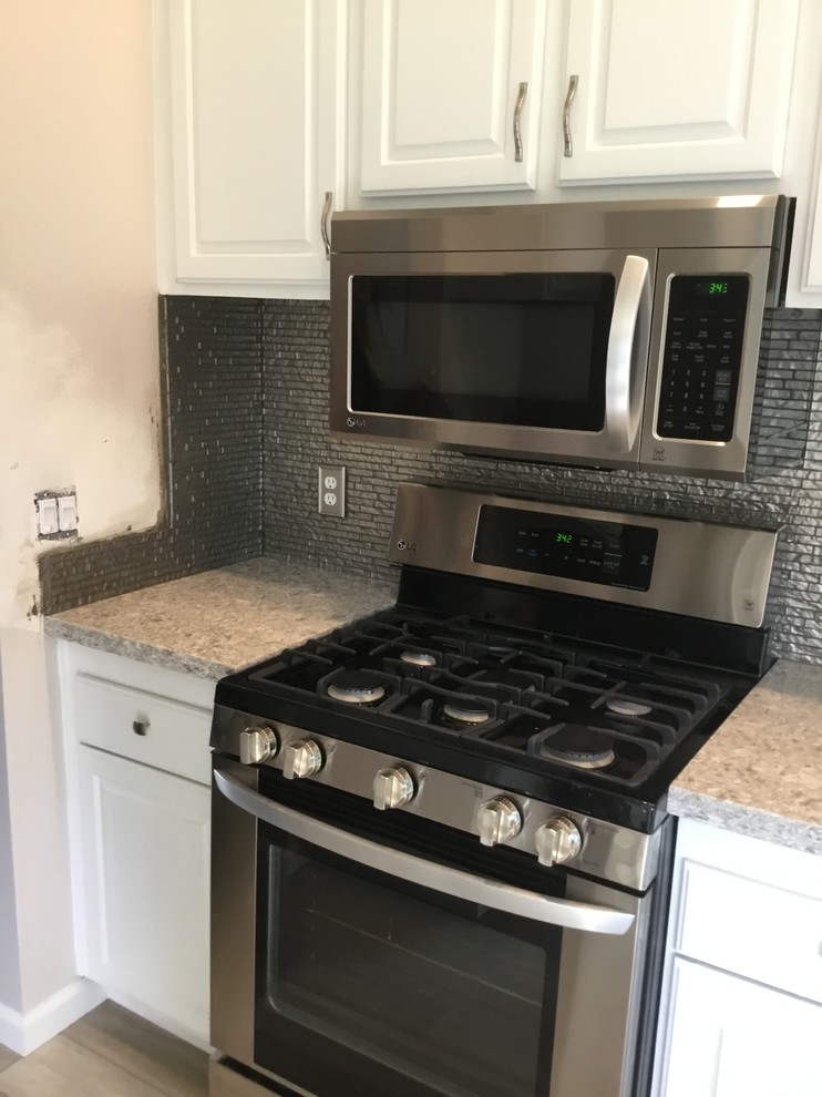 Example of a small transitional kitchen design in Orange County with metallic backsplash, glass sheet backsplash and gray countertops