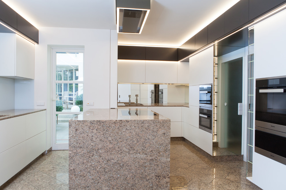 Inspiration for a mid-sized contemporary galley separate kitchen in Hanover with an undermount sink, flat-panel cabinets, white cabinets, marble benchtops, white splashback, glass sheet splashback, black appliances, marble floors, with island, pink floor and multi-coloured benchtop.