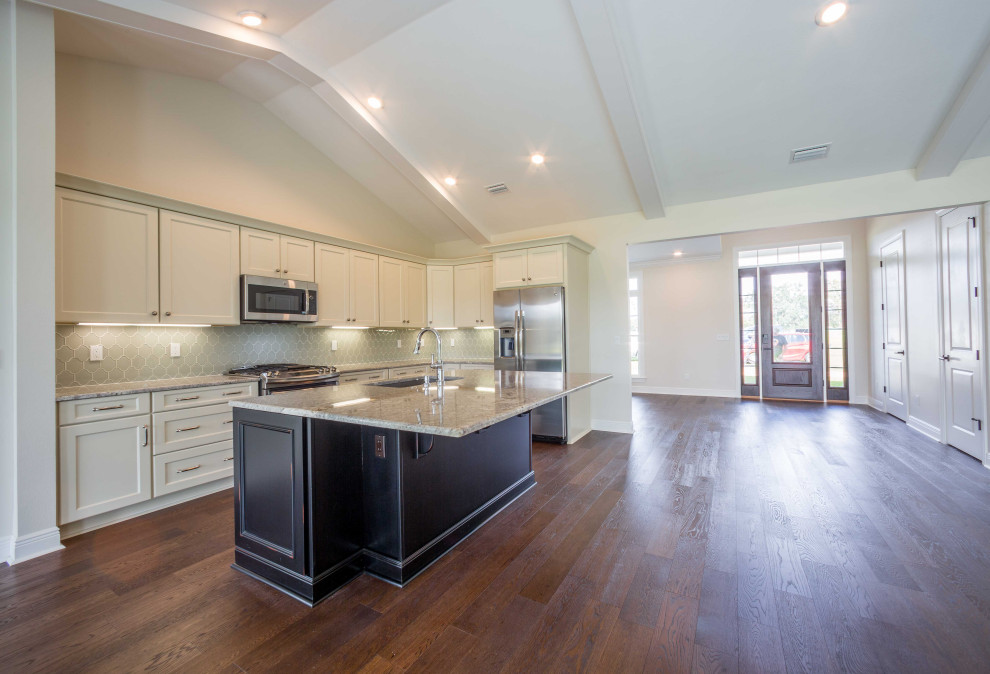 Mid-sized elegant galley medium tone wood floor and brown floor eat-in kitchen photo with an undermount sink, recessed-panel cabinets, white cabinets, granite countertops, green backsplash, glass tile backsplash, stainless steel appliances, an island and multicolored countertops