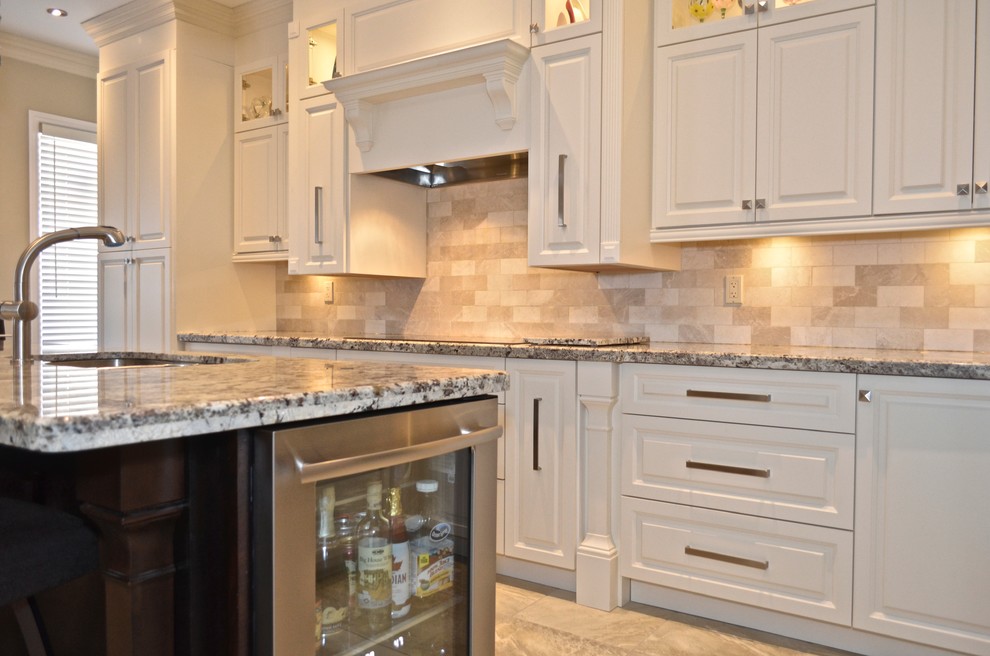 Mid-sized transitional l-shaped porcelain tile enclosed kitchen photo in Toronto with an undermount sink, raised-panel cabinets, white cabinets, granite countertops, beige backsplash, stainless steel appliances and an island