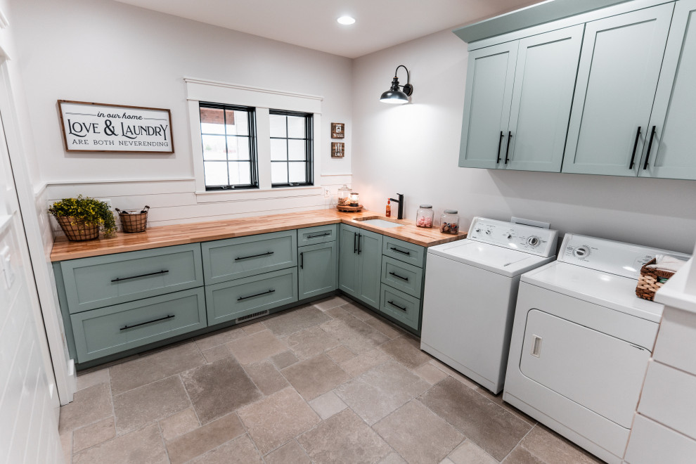 Inspiration for a large cottage l-shaped ceramic tile and gray floor dedicated laundry room remodel in Other with an undermount sink, shaker cabinets, blue cabinets, wood countertops, white backsplash, shiplap backsplash, white walls, a side-by-side washer/dryer and brown countertops