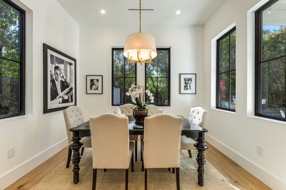 This is an example of a mid-sized transitional separate dining room in Los Angeles with white walls, light hardwood floors, brown floor and no fireplace.