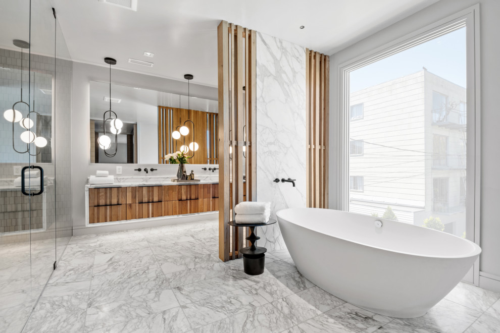 Photo of a large contemporary master bathroom in San Francisco with medium wood cabinets, a freestanding tub, a curbless shower, a wall-mount toilet, beige tile, ceramic tile, yellow walls, marble floors, a drop-in sink, marble benchtops, a hinged shower door, yellow benchtops, an enclosed toilet, a double vanity, a floating vanity, multi-coloured floor and flat-panel cabinets.