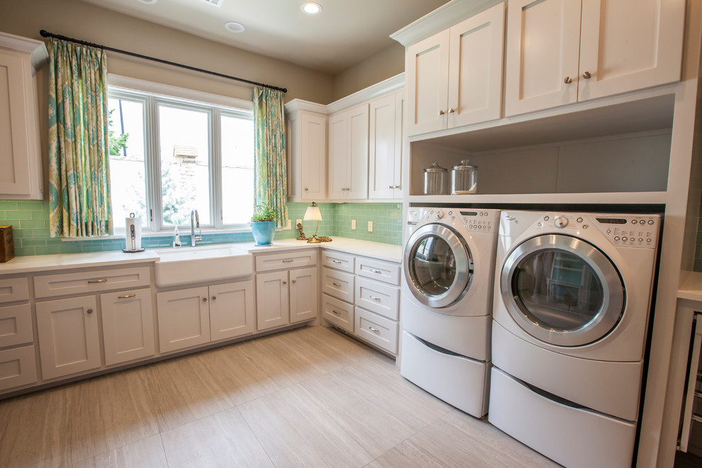 Photo of a large transitional l-shaped dedicated laundry room in Oklahoma City with a farmhouse sink, shaker cabinets, white cabinets, quartz benchtops, beige walls, porcelain floors, a side-by-side washer and dryer, beige floor and beige benchtop.