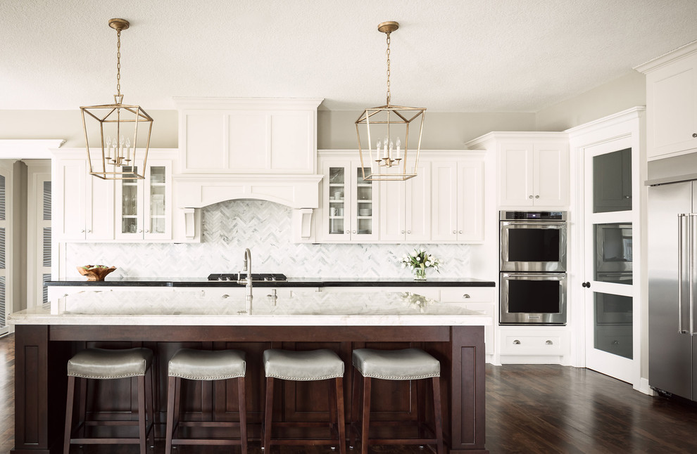 Eat-in kitchen - large transitional l-shaped dark wood floor eat-in kitchen idea in Kansas City with a farmhouse sink, shaker cabinets, white cabinets, granite countertops, gray backsplash, ceramic backsplash, stainless steel appliances and an island