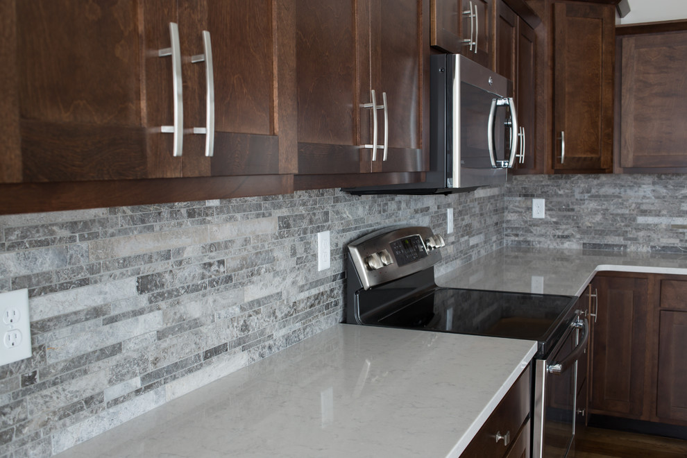 Example of a mid-sized transitional l-shaped dark wood floor enclosed kitchen design with a double-bowl sink, shaker cabinets, dark wood cabinets, quartz countertops, gray backsplash, stone tile backsplash, stainless steel appliances and an island