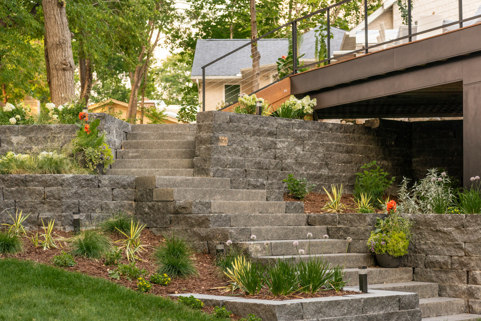 Geometrischer, Mittelgroßer, Halbschattiger Moderner Gartenkamin im Sommer, hinter dem Haus mit Mulch und Metallzaun in Minneapolis