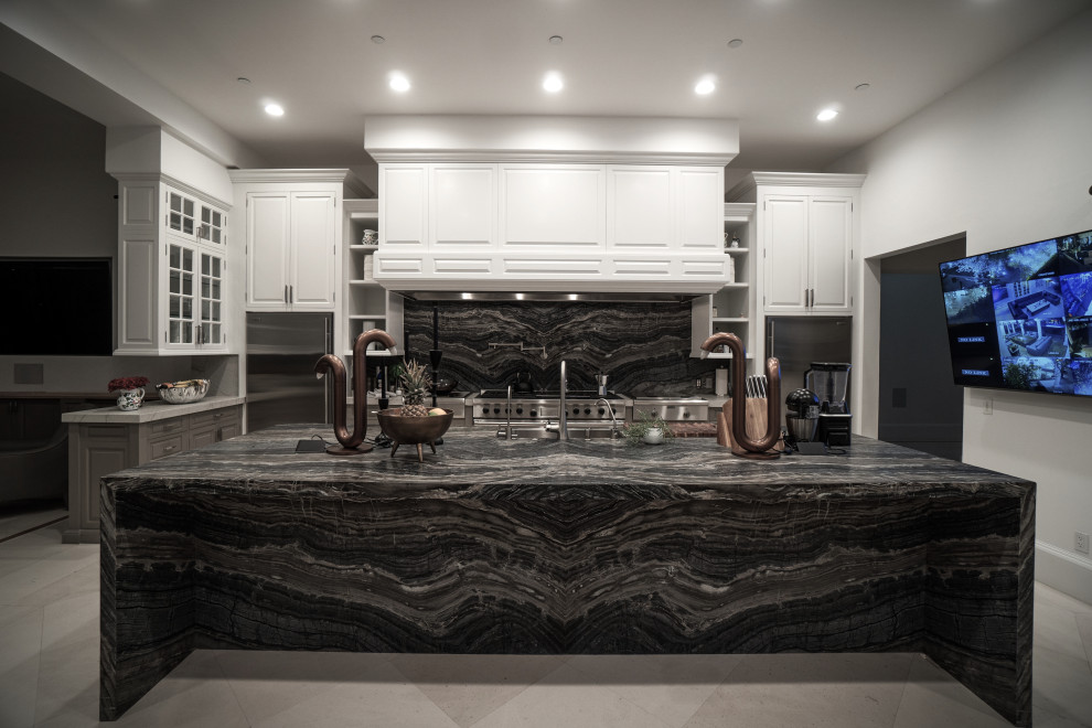 Eat-in kitchen - huge transitional l-shaped medium tone wood floor, beige floor and coffered ceiling eat-in kitchen idea in Los Angeles with an undermount sink, raised-panel cabinets, white cabinets, recycled glass countertops, black backsplash, marble backsplash, stainless steel appliances, an island and black countertops
