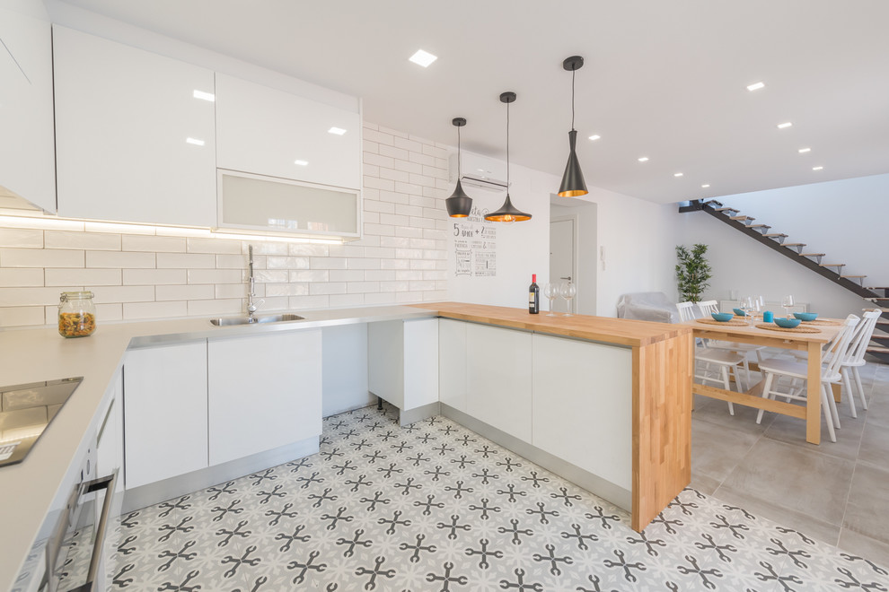 Design ideas for a large contemporary u-shaped open plan kitchen in Palma de Mallorca with an integrated sink, flat-panel cabinets, white cabinets, subway tile splashback, stainless steel appliances, ceramic floors and a peninsula.